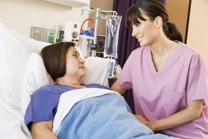 ležící žena v nemocni s ošetřovatelkou