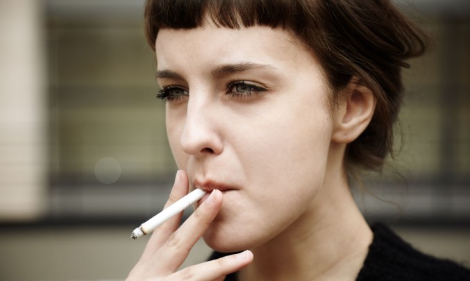 žena kouří balenou cigaretu