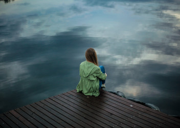 Osamělá dívka sedí na molu
