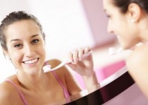 hezká mladá žena si čiští zuby v koupelně