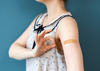 Ženská paže s náplastí po očkování