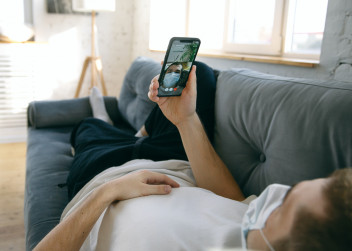 Muž s mobilním telefon leží na gauči