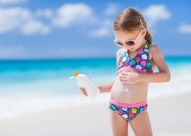 holčička se maže opalovacím krémem na pláži u moře